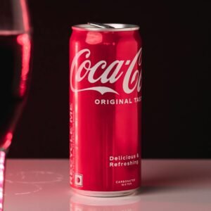 Coca-Cola can with glass reflection on a sleek surface, perfect for advertising.